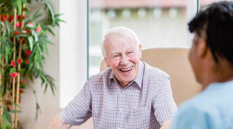 An elderly man laughing with a carer at his care home in Bristol