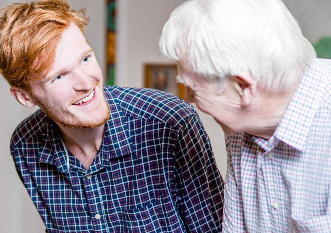 A young man talking to an elderly man with dementia